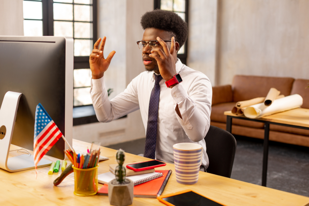 Man at computer, hands raised in frustration